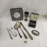 A mixed lot of silver items including silver fronted clock, silver buckle, silver sugar nips,