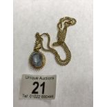 A 9ct gold chain (4 grams) with a yellow metal pendant set pale blue stone.
