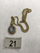 A 9ct gold chain (4 grams) with a yellow metal pendant set pale blue stone.