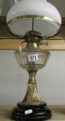 A brass oil lamp with clear glass font and complete with shade and chimney.