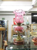 A Victorian oil lamp with cranberry glass shade.