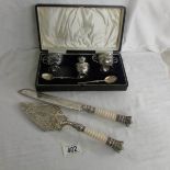 A cased silver plate cruet set together with a cake knife and slice with crown finials.
