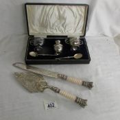 A cased silver plate cruet set together with a cake knife and slice with crown finials.