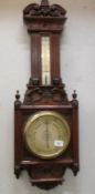 A carved oak barometer/thermometer.