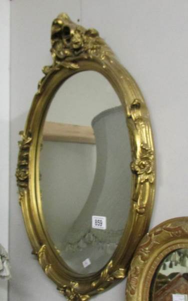 An oval gilt framed mirror.