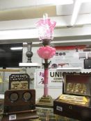 A Victorian pink column Corinthian oil lamp with Art Nouveau relief pink glass font and original