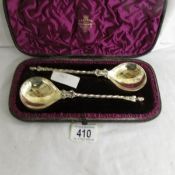 A cased set of 2 silver spoons (possibly Liturgical / Eucharist) featuring a boy at the neck,