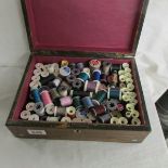 A Victorian rosewood box containing reels of cotton thread.