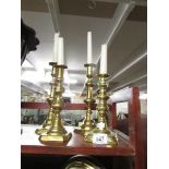 A pair of brass candlesticks and one other.