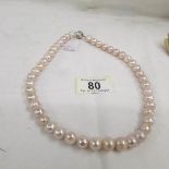 A necklace of Baroque fire ball pearls in a soft pink colour.