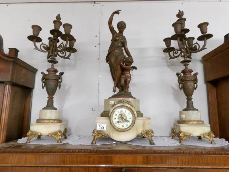 A 3 piece clock garniture comprising clock surmounted mother with child and pair of candelabra.