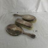 A silver backed hand mirror and 2 brushes, monogrammed.
