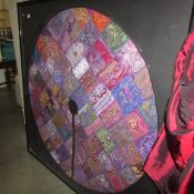 A large framed and glazed Eastern silk circular patchwork table cloth, approximately 162 x 165 cm.