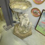 An ornate figural garden bird bath.