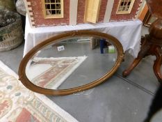 A bevel edged mirror in oval gilt frame.