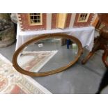 A bevel edged mirror in oval gilt frame.