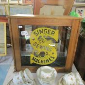 A small shelved cabinet advertising Singer sewing machines.