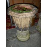 A stone urn planter on a raised stone pedestal