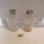 A pair of glass scent bottles with white metal caps.