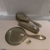 A silver backed hair brush, hand mirror and clothes brush.