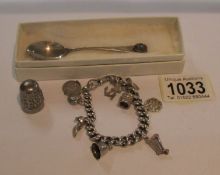 A silver charm bracelet with charms including silver, a silver teaspoon and a thimble,