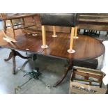 A dark wood stained extending dining table on brass lions paw castors