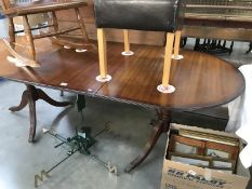 A dark wood stained extending dining table on brass lions paw castors