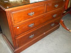 A mahogany chest of drawers with glass top.