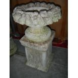 A stone urn planter on a raised stone pedestal