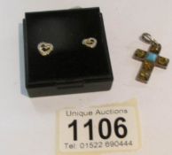 A pair of silver heart shaped ear studs and a silver stone set cross.
