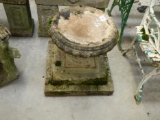 A stone bird bath on plinth
