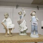 Three Lladro figurines being lady holding bird, boy reading and boy with accordion.