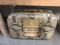 A vintage De Luxe radio with faux snake skin case