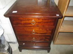 A dark wood stained bedside chest of drawers