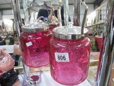 A pair of cranberry biscuit barrels with silver plated fittings