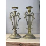 A pair of lyre style brass candlesticks