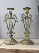 A pair of lyre style brass candlesticks