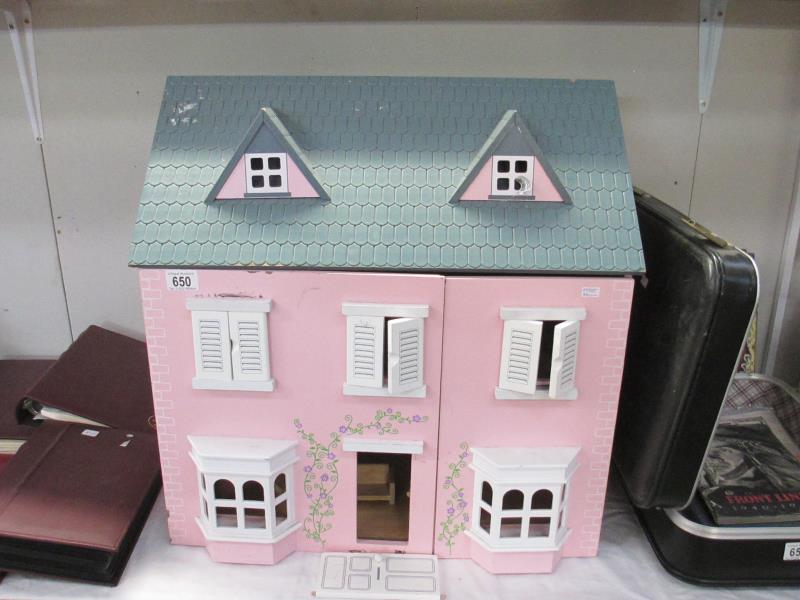 A wooden dolls house with some furniture