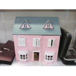 A wooden dolls house with some furniture
