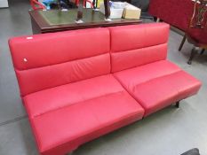 A modern design red faux leather two seater seat which easily converts to a bed
