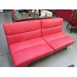 A modern design red faux leather two seater seat which easily converts to a bed