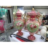 A pair of large early 20th century pink and gilded floral decorated lidded urns