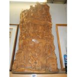 A large carved wooden sculpture featuring a procession walking up the hill
