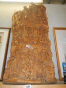 A large carved wooden sculpture featuring a procession walking up the hill