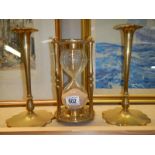 A pair of brass candlesticks and a large brass egg timer