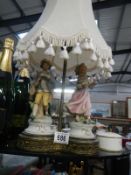 A figural lamp featuring a boy and girl with shade
