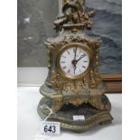 An ornate mantel clock surmounted by a cherub