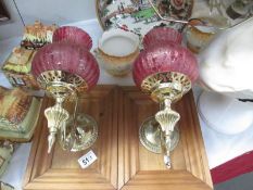 A pair of wall lamps with cranberry style shades on wooden mounts