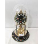 A Bidi anniversary clock with enamelled dial and under a glass dome.