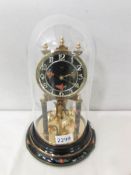 A Bidi anniversary clock with enamelled dial and under a glass dome.